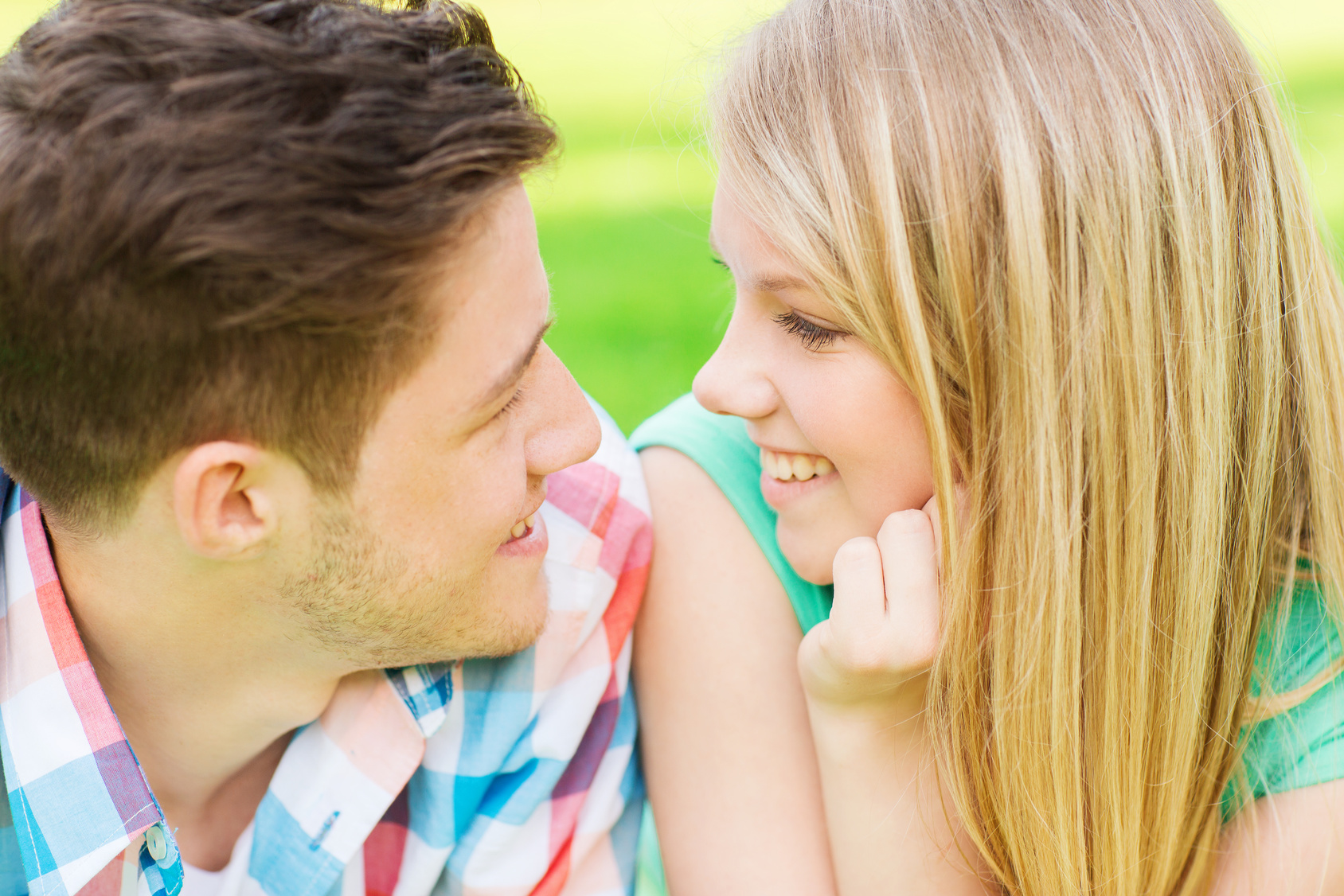 smiling couple looking at each other in park